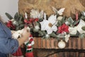 hands decorate festive a Christmas tree garland with lights, glowing bulbs, toys, bows, knitted shoes, balls, poinsettia