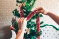 Hands decorating Christmas tree with red tinsel