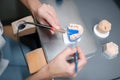 Hands of dental technician aligning teeth on prosthesis.