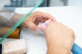 The hands of a dental technician are working on an artificial tooth using a dental instrument, a drill.