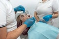 Hands of dentist and female assistant in blue gloves work with dental tools. Royalty Free Stock Photo