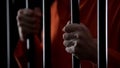 Hands of desperate arrested male holding prison bars, unfair judgment, close up