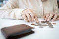 Hands of desperate asian woman is counting her last remaining coins from her wallet on white table,poverty and absence of money,