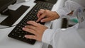 Hands of determined female scientist feverishly typing on computer amidst the hustle of lab research