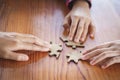 Hands of diverse people assembling jigsaw puzzle, team put pieces together searching for right match, help support in teamwork to Royalty Free Stock Photo