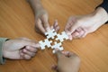 Hands of diverse people assembling jigsaw puzzle, team put pieces together searching for right match, help support in teamwork to Royalty Free Stock Photo