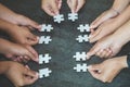 Hands of diverse people assembling jigsaw puzzle, team put pieces together searching for right match, help support in teamwork to Royalty Free Stock Photo