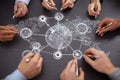 Hands of diverse people drawing a connected network diagram on a black surface, symbolizing teamwork and collaboration Royalty Free Stock Photo