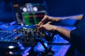 Hands of DJ playing music on rave party in night club. Professional disc jockey mixing musical tracks on stage