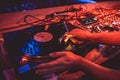 Hands of a DJ putting a vinyl record on a record player in a music club in the rays of blue and red light Royalty Free Stock Photo