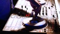 Hands of DJ tweak various track controls on DJ mixer console at nightclub