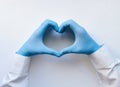 Hands of a doctor or nurse in medical gloves depict a heart on a white background, caring doctor and medicine concept Royalty Free Stock Photo