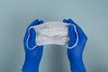 The hand of a doctor, nurse or scientist in blue gloves holds a medical mask for protection against infection isolated on a gray-b Royalty Free Stock Photo