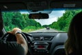 Hands of a driver on steering wheel of a car and empty asphalt road. Forest on the sides Royalty Free Stock Photo