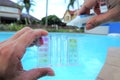 Hands dropping chemicals in test kit, swimming pool water quality maintenance