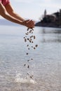 Hands dropping small stones in the sea