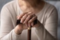 Hands of elder woman holding knob of walking cane