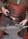 Hands of an elderly blacksmith working iron with a hammer and th Royalty Free Stock Photo
