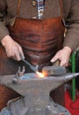 Hands of an elderly blacksmith working iron with a hammer and th Royalty Free Stock Photo