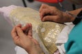 hands of the elderly while embroidering a lace