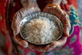 hands of elderly indian woman holding a bowl of rice