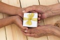 Hands of an elderly man and children`s hands are holding a box with a gift. Royalty Free Stock Photo
