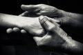 Hands of an elderly man holding the hand of a younger man. Royalty Free Stock Photo