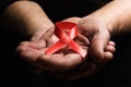 Hands of an elderly man holding the red aids ribbon. Lots of tex