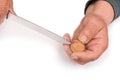 Hands of an elderly man with a knife cracking a walnut in his hand on a white background, Royalty Free Stock Photo