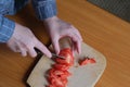 Hands of an elderly woman cutting a red ripe tomato Royalty Free Stock Photo