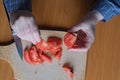 Hands of an elderly woman cutting a red ripe tomato Royalty Free Stock Photo