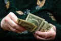 In the hands of an elderly woman are dollar bills