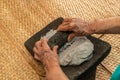 Hands of an elderly woman, grinding dough in the metate for the elaboration of blue tortillas, which is a typical Mexican food