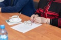 Hands of elderly woman are holding elegant steel-rimmed spectaclesa cup of tea on office table. Older people in business Royalty Free Stock Photo