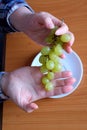 The hands of an elderly woman holds a small brush of white seedless grapes Royalty Free Stock Photo