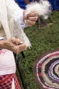 Hands of an elderly woman who weaves wool thread using a spindle