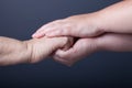 Hands of elderly and young women on black background Royalty Free Stock Photo