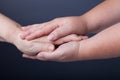 Hands of elderly and young women on black background Royalty Free Stock Photo