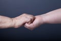 Hands of elderly and young women on black background Royalty Free Stock Photo