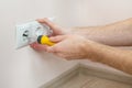 The hands of an electrician installing a wall power socket with screwdriver. Royalty Free Stock Photo