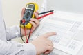 Hands of engigeer on control panel of industrial equipment closeup. Engineer with multimeter adjusts technology process