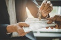 Hands of estate agent giving keys to the customer and bank note