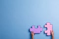 The hands of the man hold large pink and lilac color puzzles. Blue background with a place for an inscription.