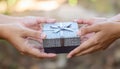 Hands Exchanging Gift Box in Outdoor Setting with Soft Natural Light Royalty Free Stock Photo