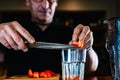 hands of an experienced bartender pouring fruit into a glass cocktail glass. Cocktail preparation in a nightclub. Royalty Free Stock Photo