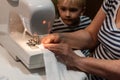 Grandmother teaches to sew of a sewing machine