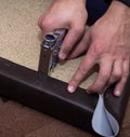 Hands fastening leatherette to the particle board using stapler