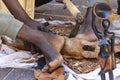 Hands and feet of an African craftsman on a market, who is working a piece of wood with a small ax to carve a figure out of it