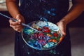 Hands of female artist holding messy dirty palette with different paints and paintbrush