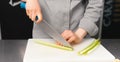 Hands of a female chef are cutting fresh green celery on a plastic board. Royalty Free Stock Photo